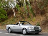 a silver convertible car driving down the road with trees in the background