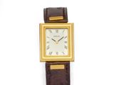 une photo d'une montre-bracelet plaquée or montée sur un bracelet en cuir marron
