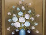 a painting of flowers in a blue vase on a easel