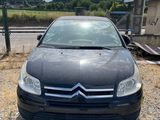 a black car parked in a gravel lot next to a fence