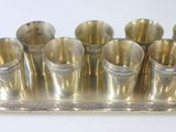 a silver tray with six silver cups on it