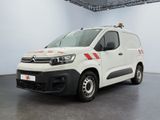 La camionnette blanche est garée dans une pièce blanche ; elle porte une bande rouge sur le côté.