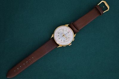 a close up of a watch on a green surface