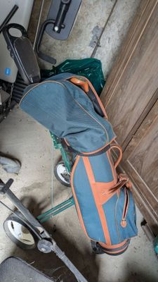 un sac de voyage bleu et orange posé par terre à côté d'une paire de chaussures