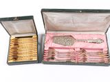 two boxes with silver and gold items inside of them