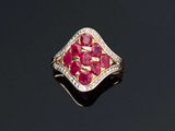 un gros plan d'une bague sertie d'un diamant et d'un rubis sur une surface noire