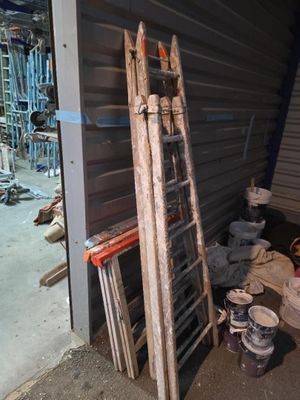 une échelle appuyée contre un mur, à côté d'une pile de seaux
