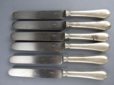 six couteaux en métal argenté avec manche, posés sur une table