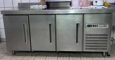 un plan de travail en acier inoxydable dans une cuisine équipée d'un réfrigérateur