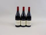 trois bouteilles de vin rouge sont posées sur une surface blanche