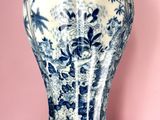 un vase bleu et blanc posé sur une surface rose