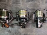three fishing reels are lined up on a wall next to each other
