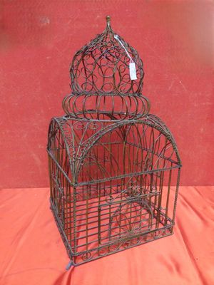 une vieille cage à oiseaux avec une étiquette, posée sur un tissu rouge