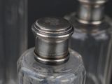 a glass bottle with a silver lid sitting next to another glass bottle