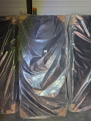 four mattresses wrapped up in plastic in a warehouse