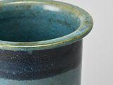 a close up of a blue vase on a white surface