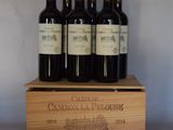 quatre bouteilles de vin rouge dans un coffret en bois posé sur une table