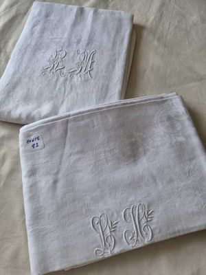 deux serviettes blanches ornées de monogrammes brodés, posées sur un lit