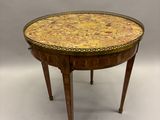 une petite table ronde dont le plateau est orné d'un motif jaune et marron