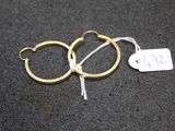 three pairs of gold hoop earrings with a price tag on a black surface