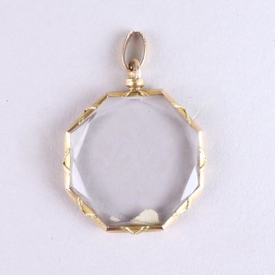 gros plan d'un pendentif plaqué or sur une surface blanche