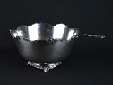 a silver bowl with a spoon in it on a black background