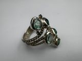 a close up of a ring with green stones on it