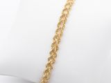 gros plan d'un bracelet en or sur un oreiller blanc