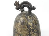 an old bell with a dragon on it sitting on a white surface