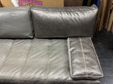 grey leather sofa with matching pillows in a warehouse area