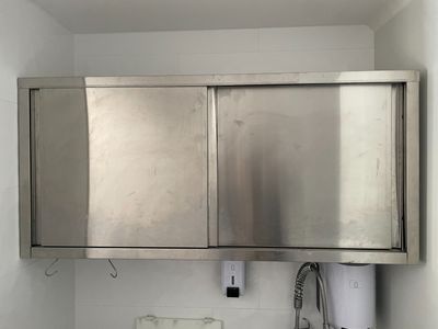une armoire à pharmacie en acier inoxydable, placée dans un coin de la salle de bains