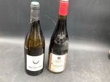 two bottles of wine sitting next to each other on a counter