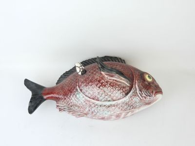 a red fish that is sitting on a white surface