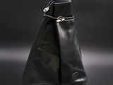sac à main en cuir noir sur fond noir, muni d'un fermoir argenté