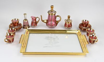 un plateau en or sur lequel est posé un service à thé en verre rose