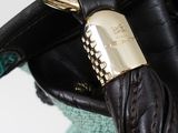 someone is holding a black purse with a gold lock on it