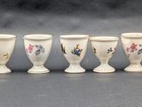 six white vases are lined up in a row on a gray surface