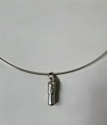 a close up of a silver necklace with a bottle on it