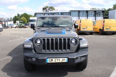 une jeep grise garée sur un parking, avec d'autres véhicules en arrière-plan