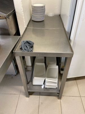 table en acier inoxydable sur laquelle sont posées des assiettes et des bols, dans une cuisine professionnelle
