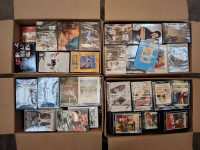 une boîte remplie de DVD et de CD posée par terre