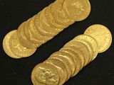 a close up of a pile of gold coins on a black surface