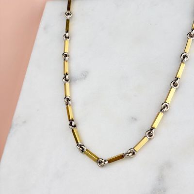 un gros plan d'un collier en or et en argent posé sur une surface en marbre