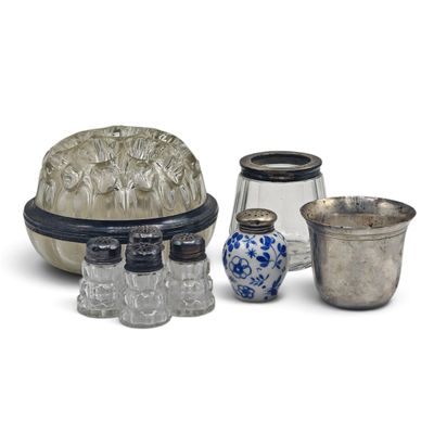 trois vases en verre et un récipient en argent posés sur une surface blanche