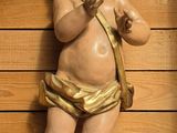 une statue représentant un bébé avec un nœud, accrochée au mur