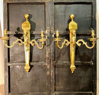 two golden sconces on the door of a building
