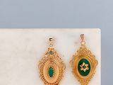 une paire de boucles d'oreilles vertes et dorées posées sur une surface en marbre