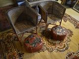 two wicker chairs and a ottoman in a room