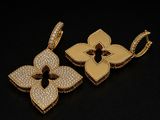two gold pendants with diamonds on a black background