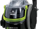 un aspirateur vert et noir muni d'un tuyau sur le dessus